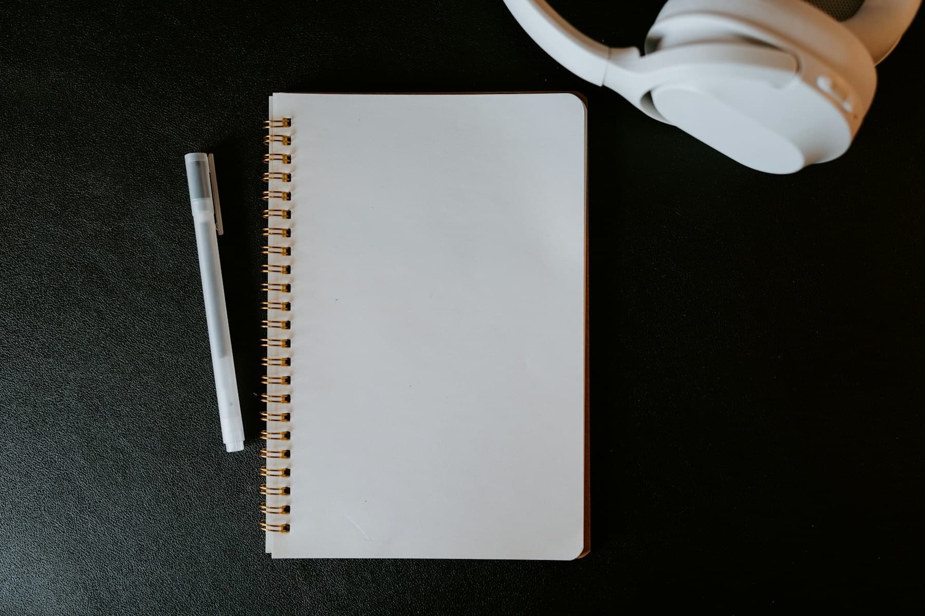 Carnet, stylo et casque sur fond sombre, pour évoquer une ressource claire et prête à l’emploi.